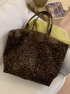 Grand sac cabas léopard pour femme posé sur un canapé blanc dans un décor cosy