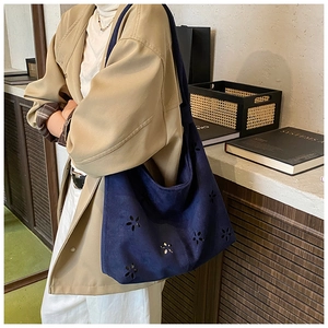 Close-up of hollow flower laser-cut patterns on navy blue suede hobo tote bag