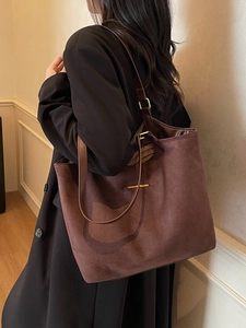 Retro brown suede tote bag with leather strap worn by model in a minimalist setting