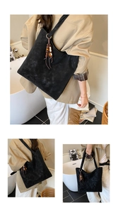 Detail of large black suede tote bag with silver rings and retro wooden bead tassels