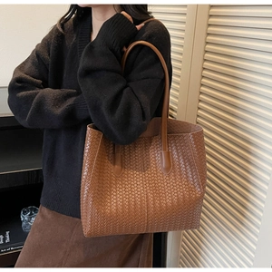 Gros plan d'un sac cabas en cuir tressé marron avec de grandes anses au style minimaliste