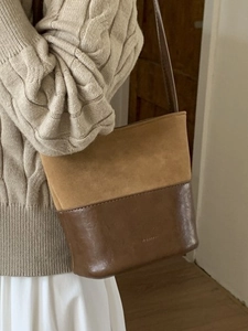 Sac seau rétro en daim camel et cuir porté par un mannequin pour l'automne hiver