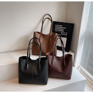 Trois sacs cabas en cuir tressé en noir et marron sur des marches minimalistes
