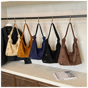 Detail of laser-cut floral pattern and suede texture on various colorful hobo bags