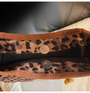 Dettaglio della chiusura magnetica della borsa leopardata e del bordo in fettuccia