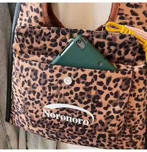 Dettaglio della borsa tote leopardata con tasca frontale, fibbia e tablet per la capacità