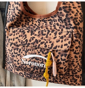 Dettaglio della borsa hobo leopardata con nappa rosa e nodo di corda gialla decorativo