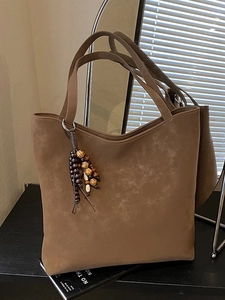 Large dark brown suede tote bag for women with vintage beaded tassel on black surface