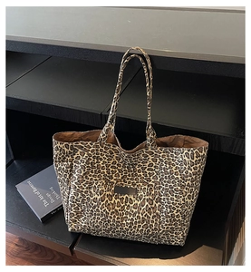 Detail of leopard print tote bag with external pocket on black display stand