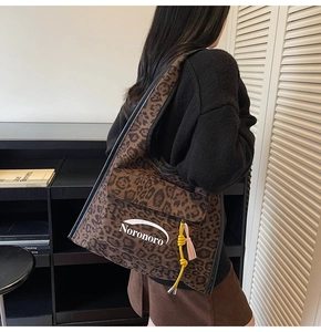 Dettaglio della borsa hobo leopardata con ciondolo a nappa e logo del marchio inciso