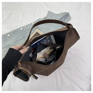 Detail of spacious brown suede tote bag interior showing daily essentials and soft texture
