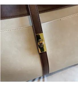 Détail macro du fermoir doré et des surpiqûres contrastées sur le sac fourre-tout