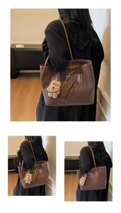 Detailed view of leopard print tote bag with plush bear charm and brand logo