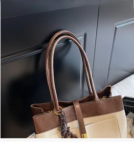 Détail des poignées durables et coutures contrastées sur un sac à main en cuir marron