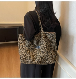 Detailed back view of a model carrying a large leopard print tote bag with flat handles