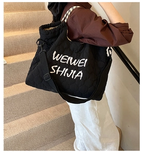 Détail du sac cabas matelassé noir avec broderie cursive et poignée à carreaux bicolore