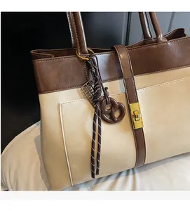 Détail du sac cabas bicolore avec fermoir rotatif et pendentif en forme de cœur tissé