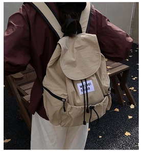 Vue de dos d'un sac à dos beige avec cordon de serrage et poches zippées noires en extérieur