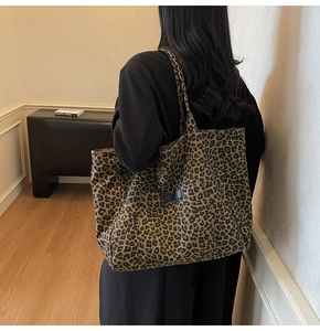 Detailed view of large leopard print tote bag worn on shoulder in a modern room