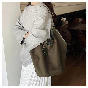 Détail d'un grand sac seau en daim olive montrant sa texture mate et sa conception spacieuse