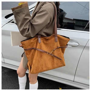 Detailed outdoor view of a caramel brown suede tote bag with vintage leather straps