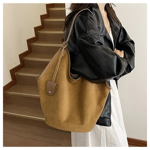 Side view of large camel suede tote bag on model showing spacious bucket design and texture
