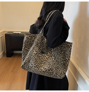 Macro detail of leopard print tote bag with black leather logo patch and wide strap
