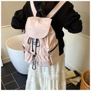 Vue détaillée du dos d'un sac à dos rose clair à cordon de serrage porté par un mannequin