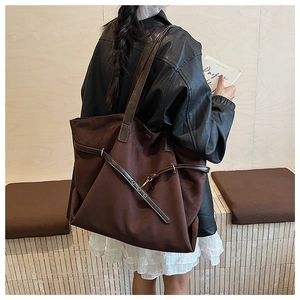 Detail of dark brown suede tote bag with slim leather straps and metal buckle accent