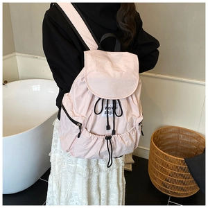 Détail du sac à dos rose pêche montrant la poche zippée latérale et l'étiquette de marque