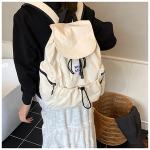 Gros plan détaillé du sac à dos crème à cordon montrant la texture nylon et le zip
