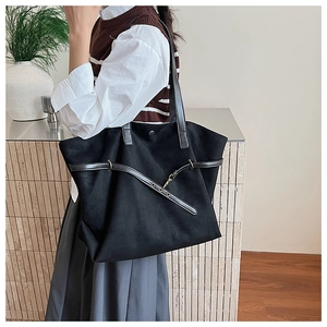 Model showing a large black suede tote bag with strap buckle and minimalist design