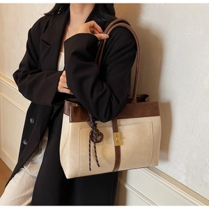 Close-up of retro cream tote bag with dark brown straps and golden square metal lock