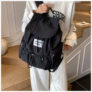 Détail d'un sac à dos noir en nylon avec cordon de serrage et poches latérales