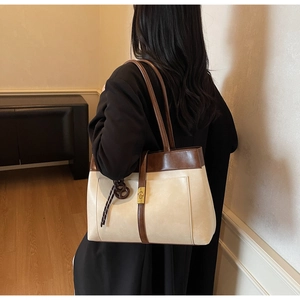 Detailed side view of large off-white tote bag with brown straps and golden buckle