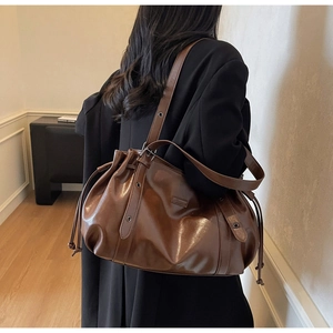 Detail showing deep brown faux leather shoulder bag with side metal eyelet and soft drawstring