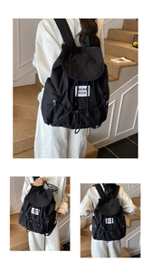 Détail du sac à dos noir en nylon avec fermeture à cordon et poche zippée latérale