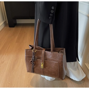 Detail of dark brown leather tote bag with gold metal buckle and vintage side strap decoration
