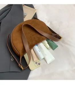 Makroaufnahme des geräumigen Innenraums der braunen Wildledertasche mit Make-up und Handy