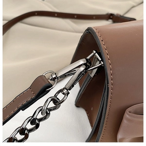 Détail de la ferrure en métal foncé avec chaîne et bandoulière réglable en cuir marron
