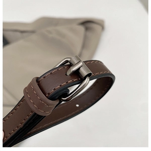 Détail de la bandoulière en cuir marron foncé avec boucle métallique et réglage précis