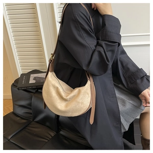Detail einer minimalistischen beige Wildleder-Hobo-Tasche mit braunem Lederriemen