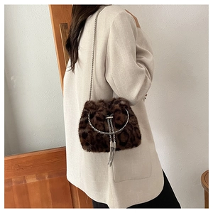 Détail du sac seau en fausse fourrure léopard avec chaîne en métal et pompons à cordon