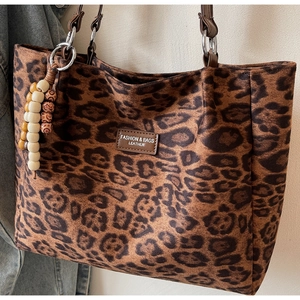 Detailed macro shot of leopard print tote bag with wooden beads and leather label