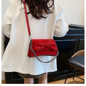 Détail du sac rouge à nœud avec bandoulière chaîne argentée et structure en accordéon