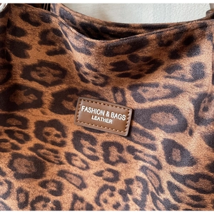 Detail of leopard print tote bag featuring a leather fashion label and soft velvet texture