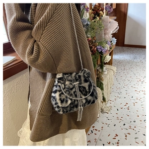 Détail du sac seau en peluche léopard avec bandoulière chaîne et pompon métallique