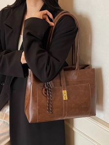 Large brown leather tote bag with metallic lock and weave charm shown on model