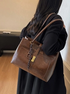 Vintage brown leather tote bag for women with gold clasp and decorative tassel pendant
