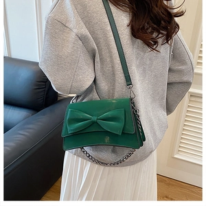 Détail du sac à bandoulière vert foncé avec grand nœud et bandoulière en chaîne métallique
